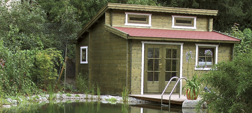 Ständerbauhaus aus Holz vor einem Weiher